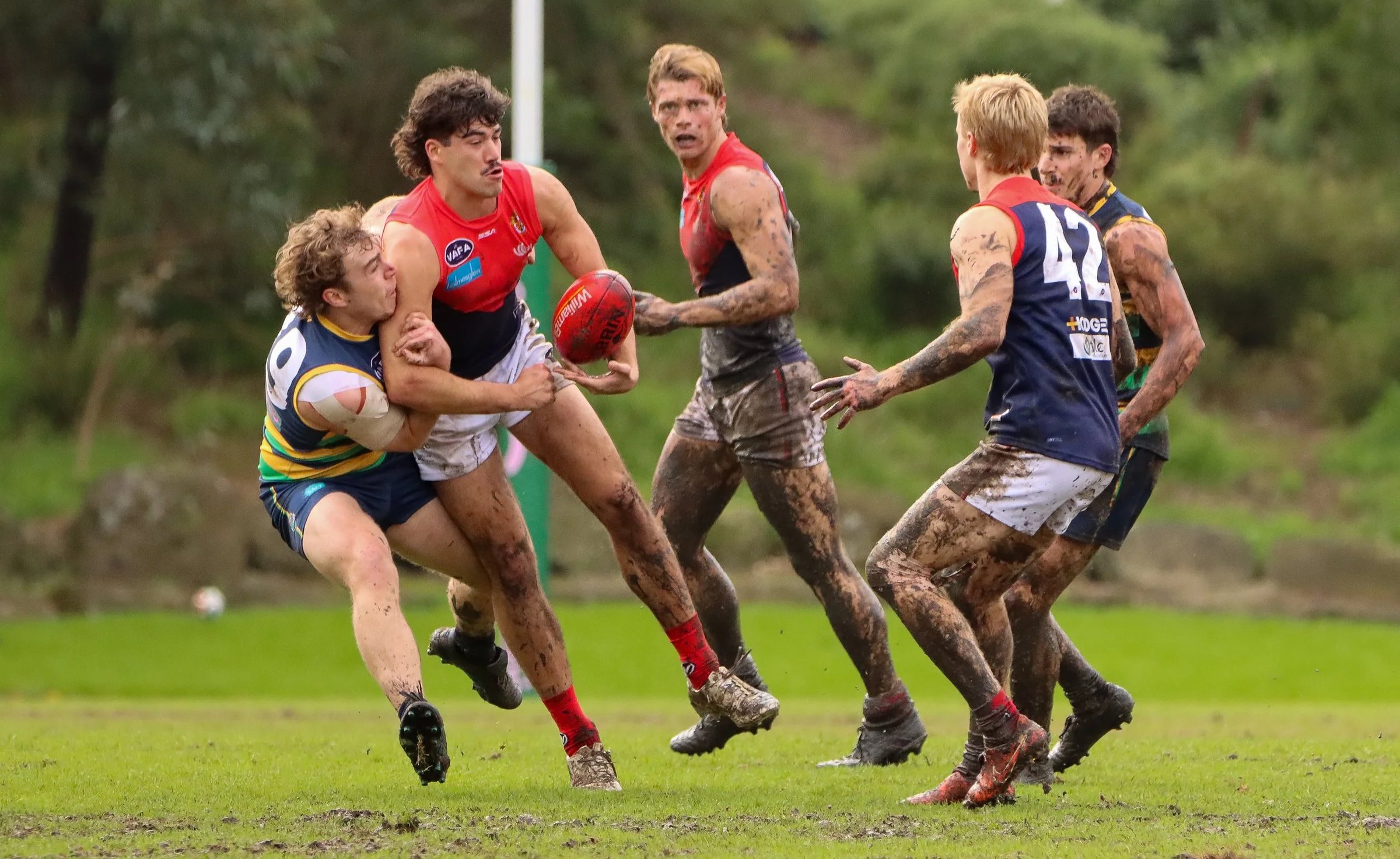 Old Brighton players break through a tackle with the ball
